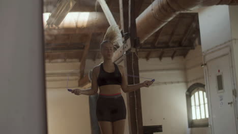 Medium-shot-of-beautiful-woman-jumping-rope-alone-in-gym